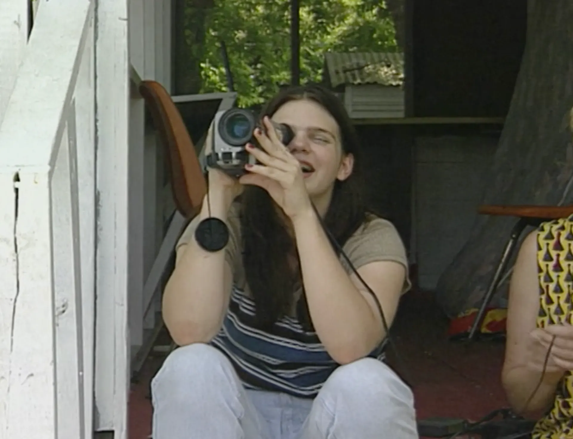 White girl looks into an old video camcorder.