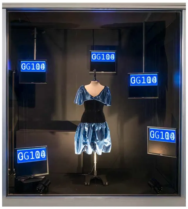 Photo of blue dress in shop window with direct lights and surrounded by five LED screens with numbers